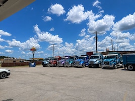 Un estacionamiento con varios camiones estacionados bajo un cielo despejado con algunas nubes.