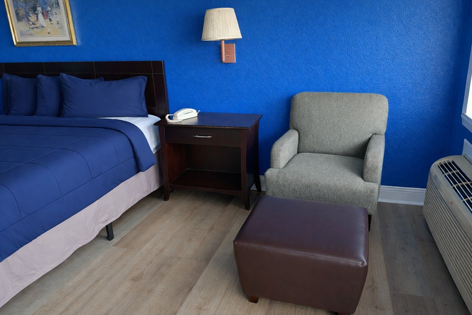 Ein Hotelzimmer mit Bett, Nachttisch, Stuhl und Heizung.