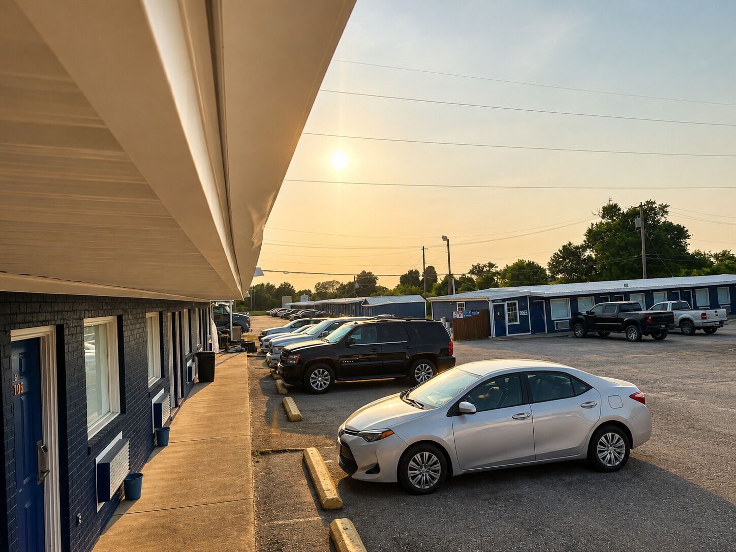 A parking lot with several cars, a building with a flat roof, and a clear sky.