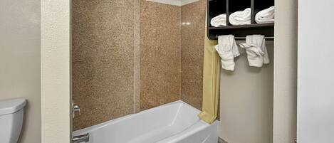 A modern bathroom with a bathtub, a shower, and a towel rack with towels.