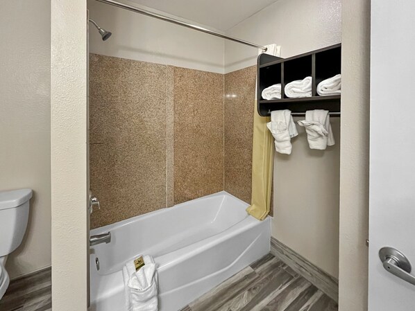 A modern bathroom with a bathtub, a shower, and a towel rack with towels. - Rodeo Lodge (Clovis)