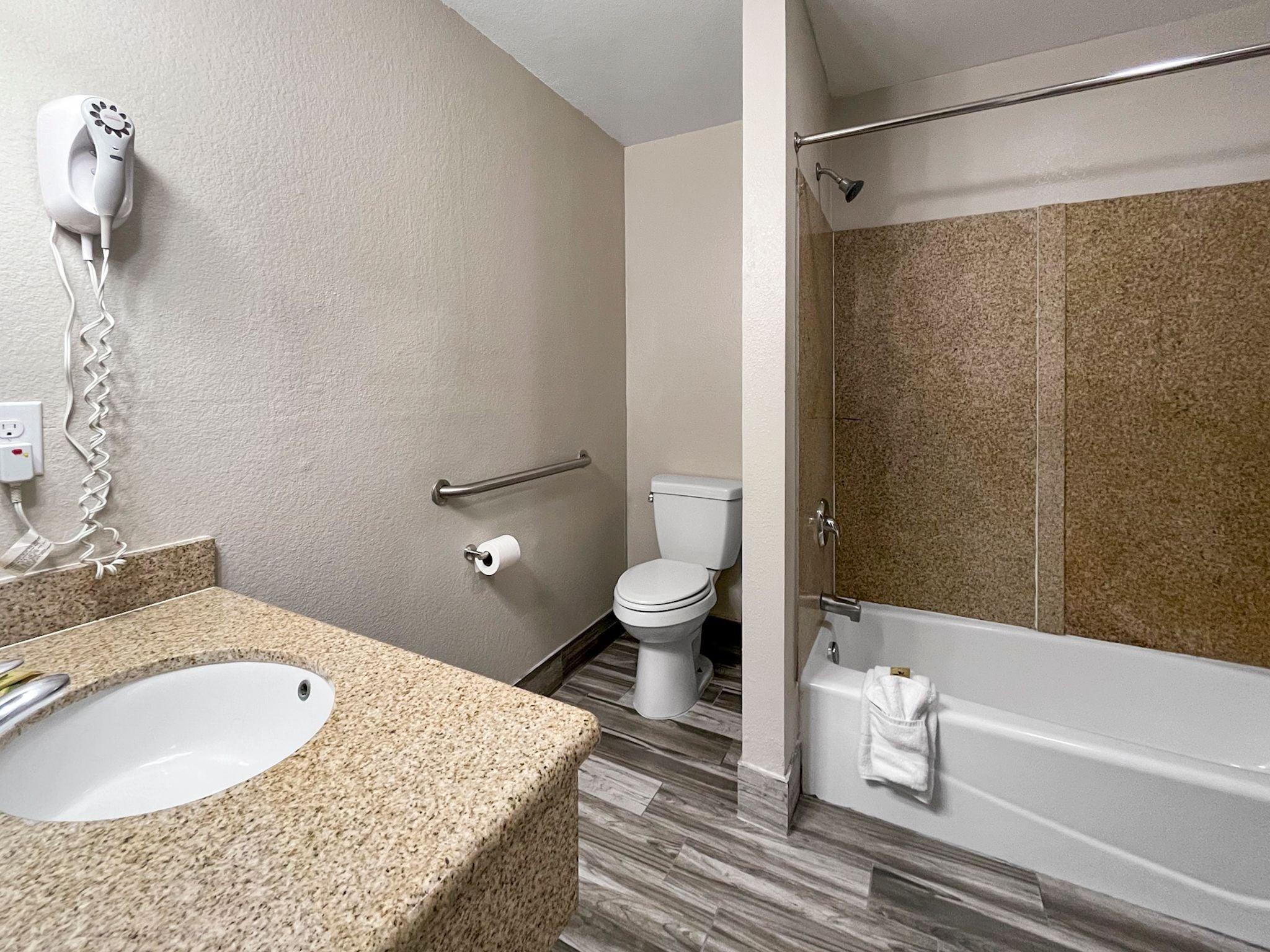 A bathroom with a granite countertop sink, a toilet, a shower with a glass door, and a towel rack.