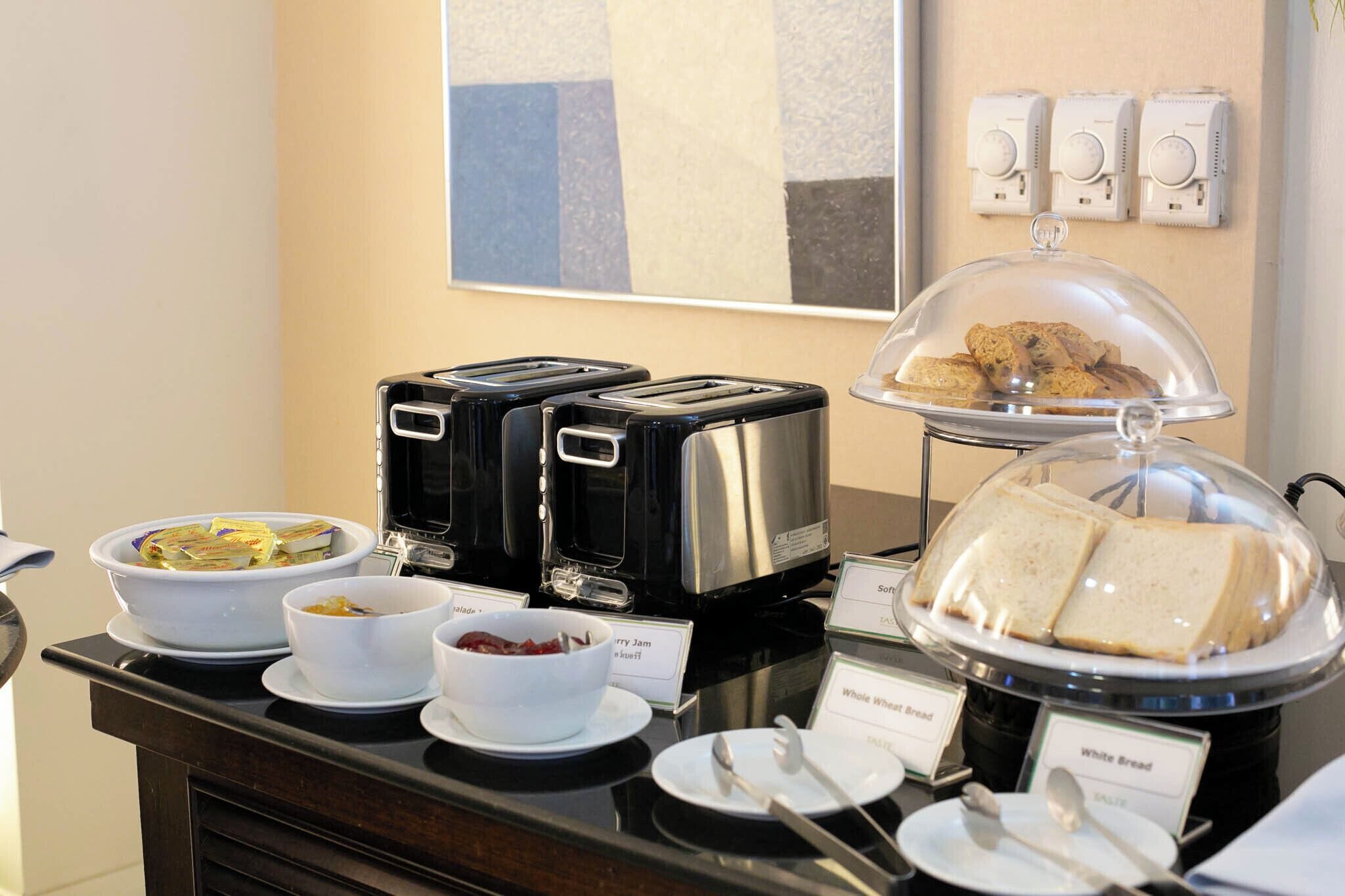 A breakfast buffet with various food items, including bread, jam, and cereal, displayed on a counter with a modern design.