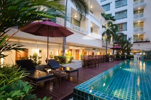 A poolside area with lounge chairs, umbrellas, and a pool. - At Ease Saladaeng by AETAS (Bangkok)