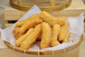 A basket of fried dough sticks on a wooden surface.