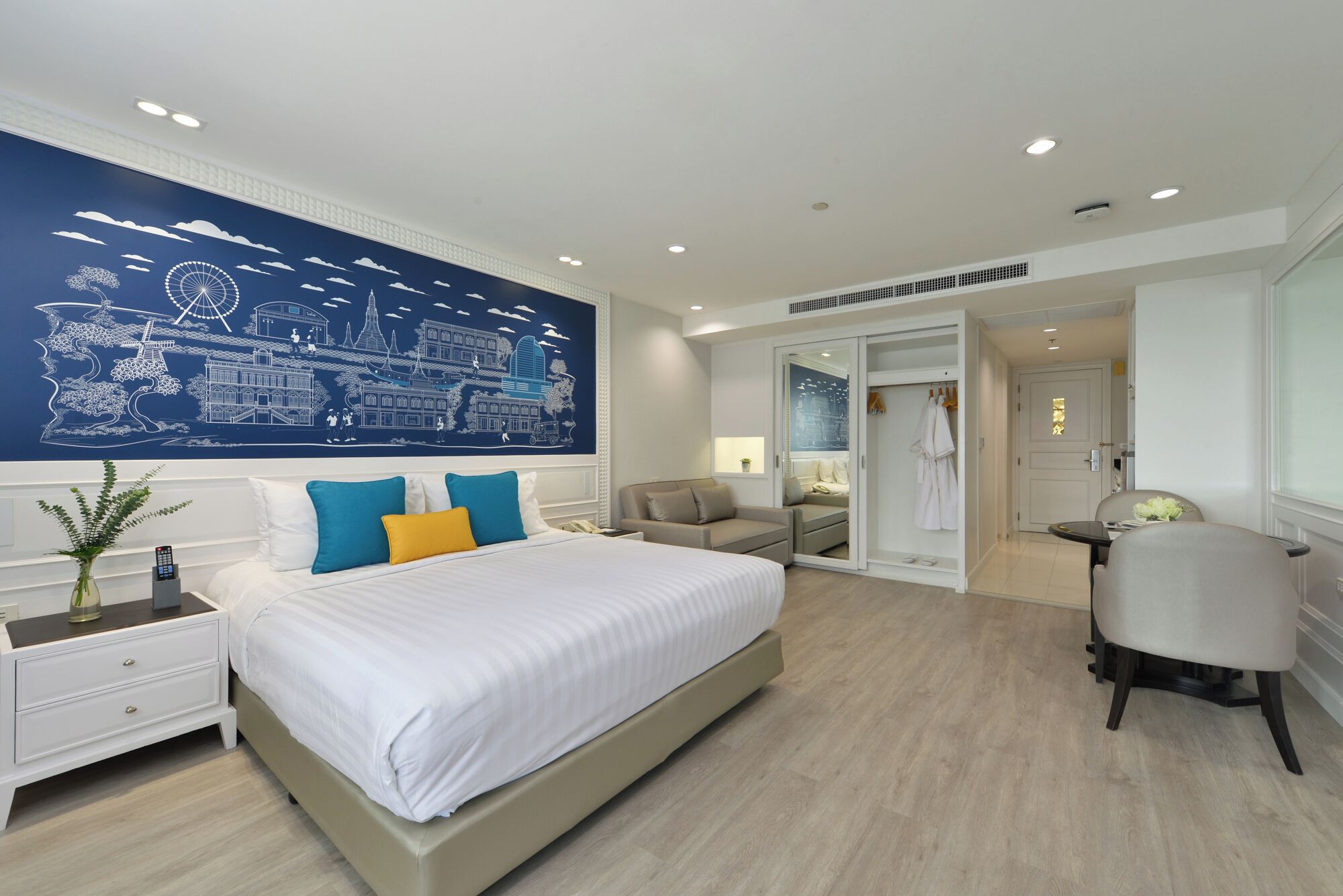 A modern hotel room with a large bed, a seating area, and a bathroom visible through an open door.