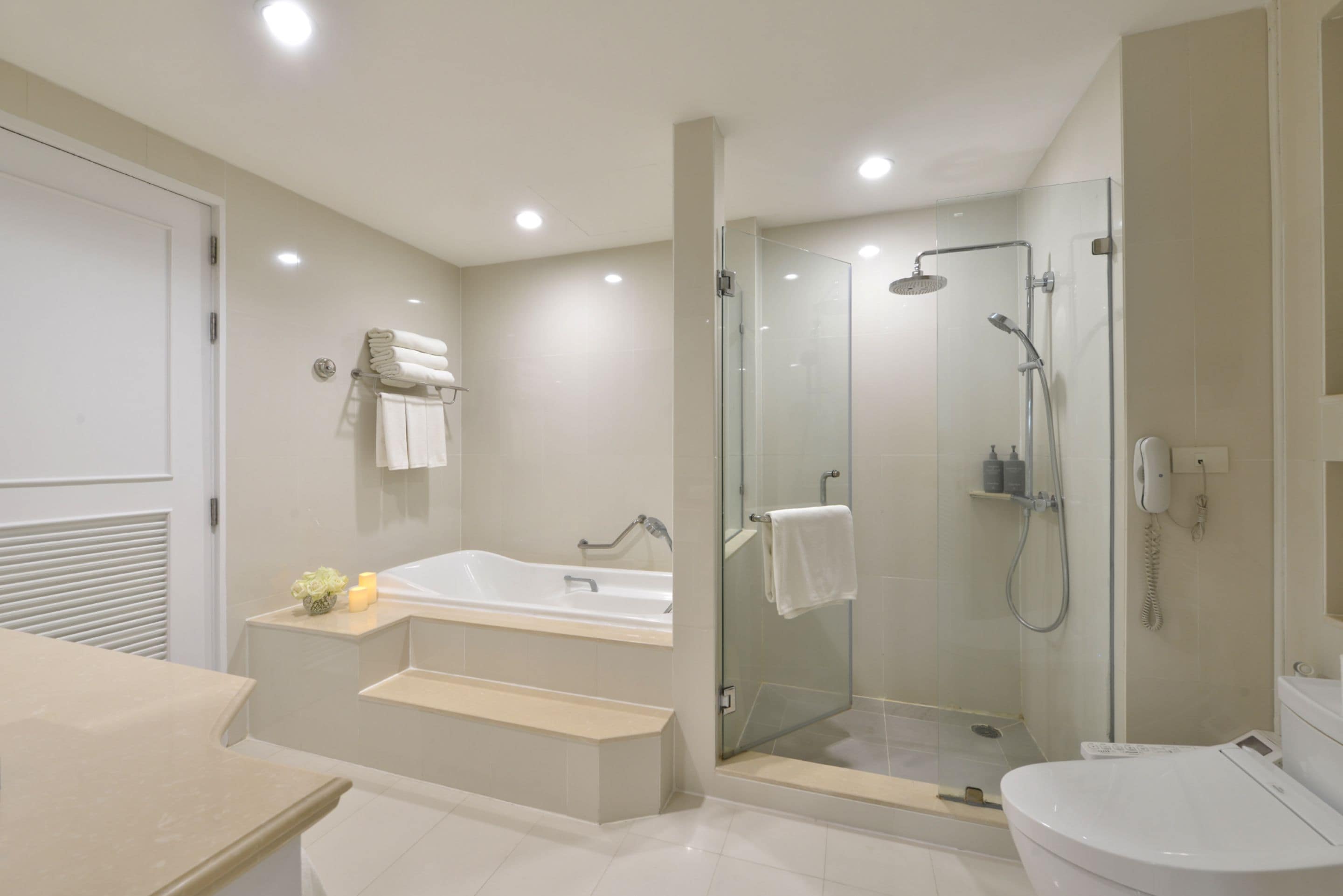 A modern bathroom with a glass-enclosed shower, a bathtub, and a toilet.