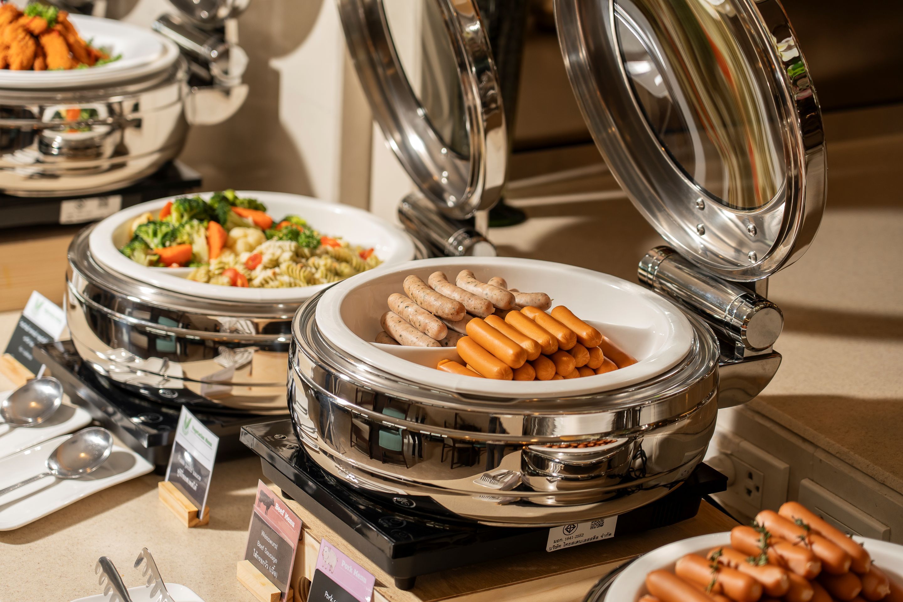 A buffet with various dishes including sausages and pasta.