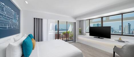 A modern hotel room with a large bed, a TV, and a city view.