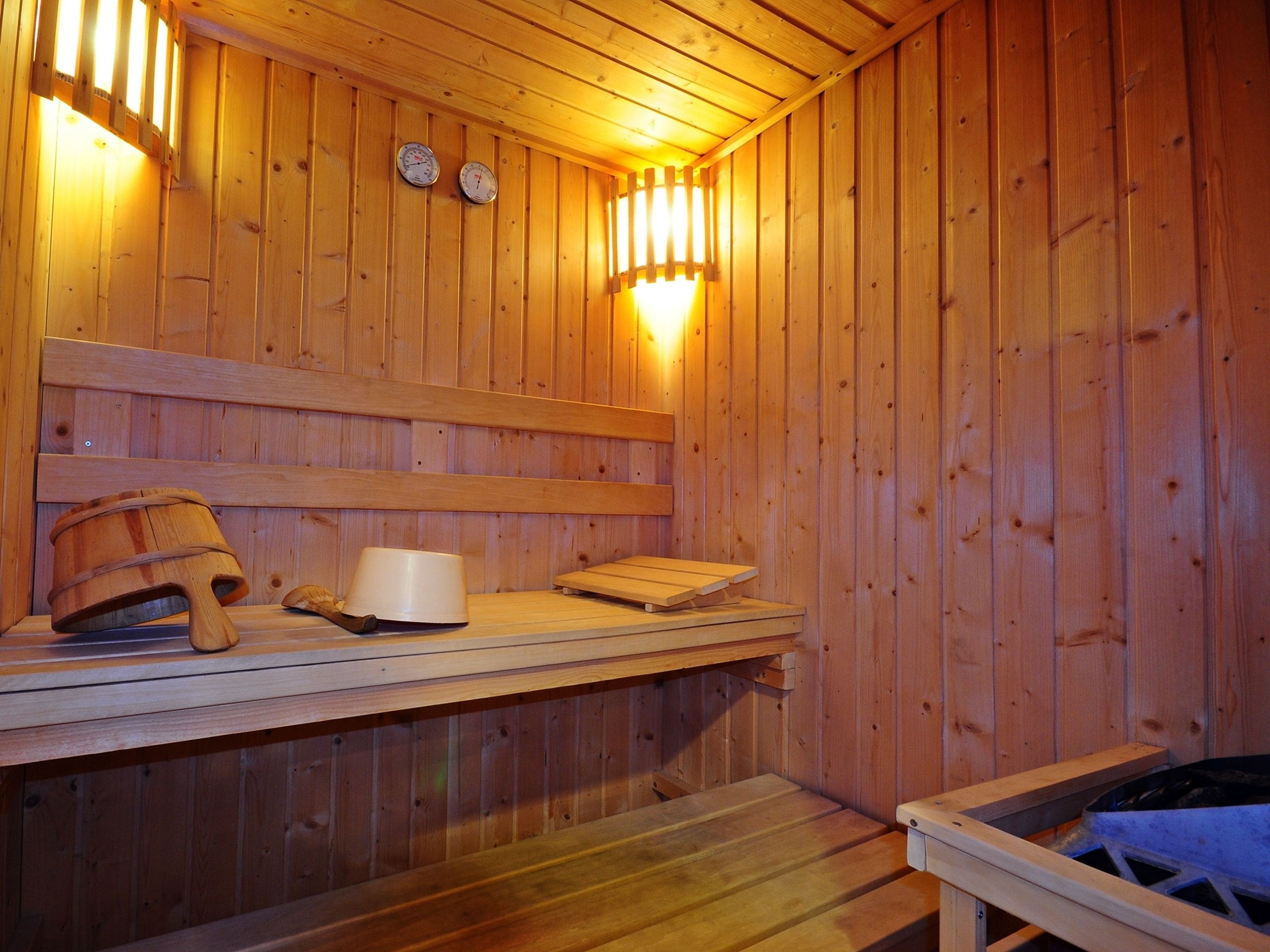Eine Holzsauna mit Bänken, einem Holzfass und einem festinstallierten Ofen.