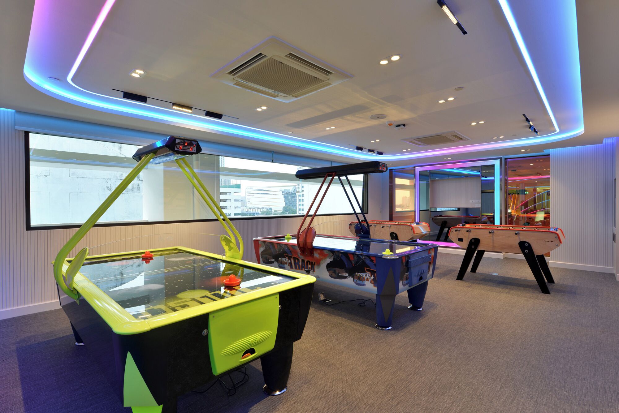 A room with a pool table, a foosball table, and a table tennis table.