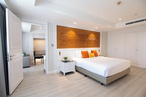 A bedroom with a large bed, a nightstand, a desk, and a wall with a cityscape mural.