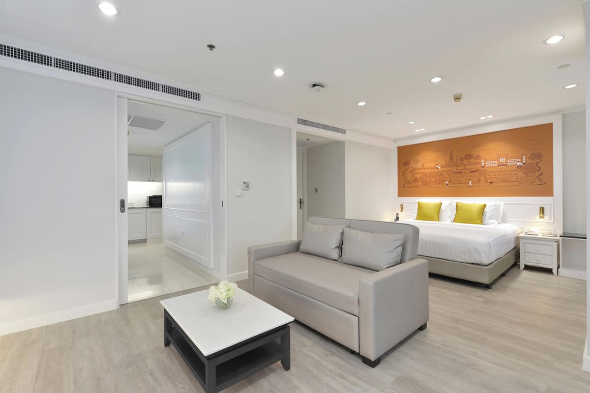 Een moderne hotelkamer met een bank, een kleintje tafeltje, een bed en een kunstwerk aan de muur.