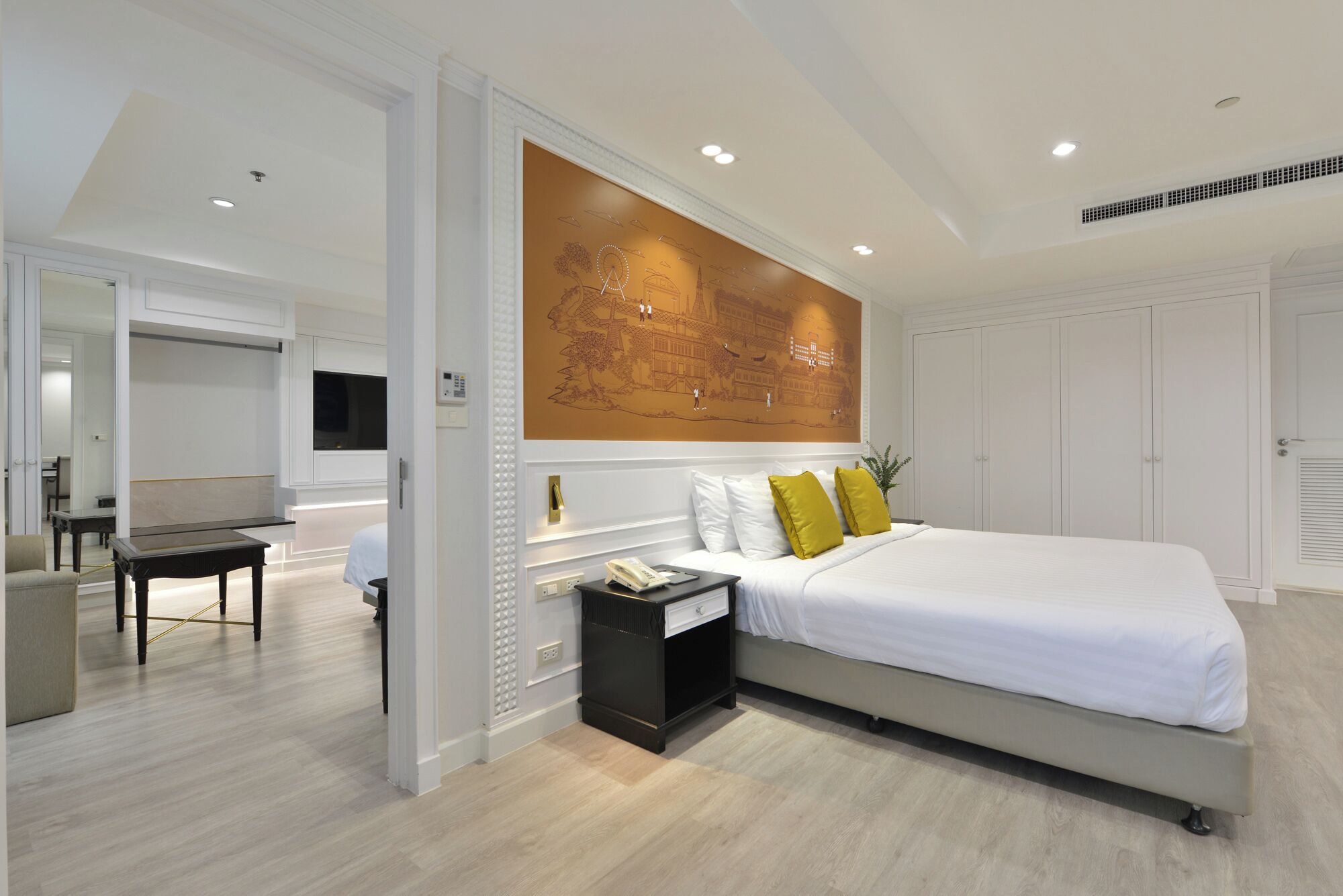 A modern bedroom with a large bed, a desk, and a wall-mounted artwork.
