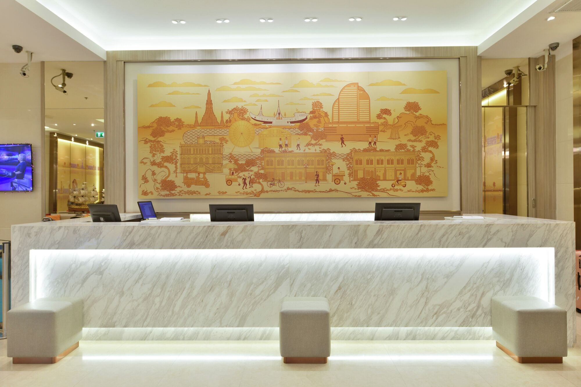 Ein Hotel-Rezeptionsbereich mit einer Marmor-Theke, einem großen Wandbild mit Stadtansicht und einem Flachbildfernseher auf der linken Seite.
