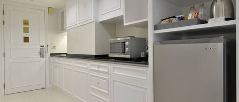 A modern kitchen with white cabinets, a microwave, a refrigerator, and a coffee maker on the countertop.