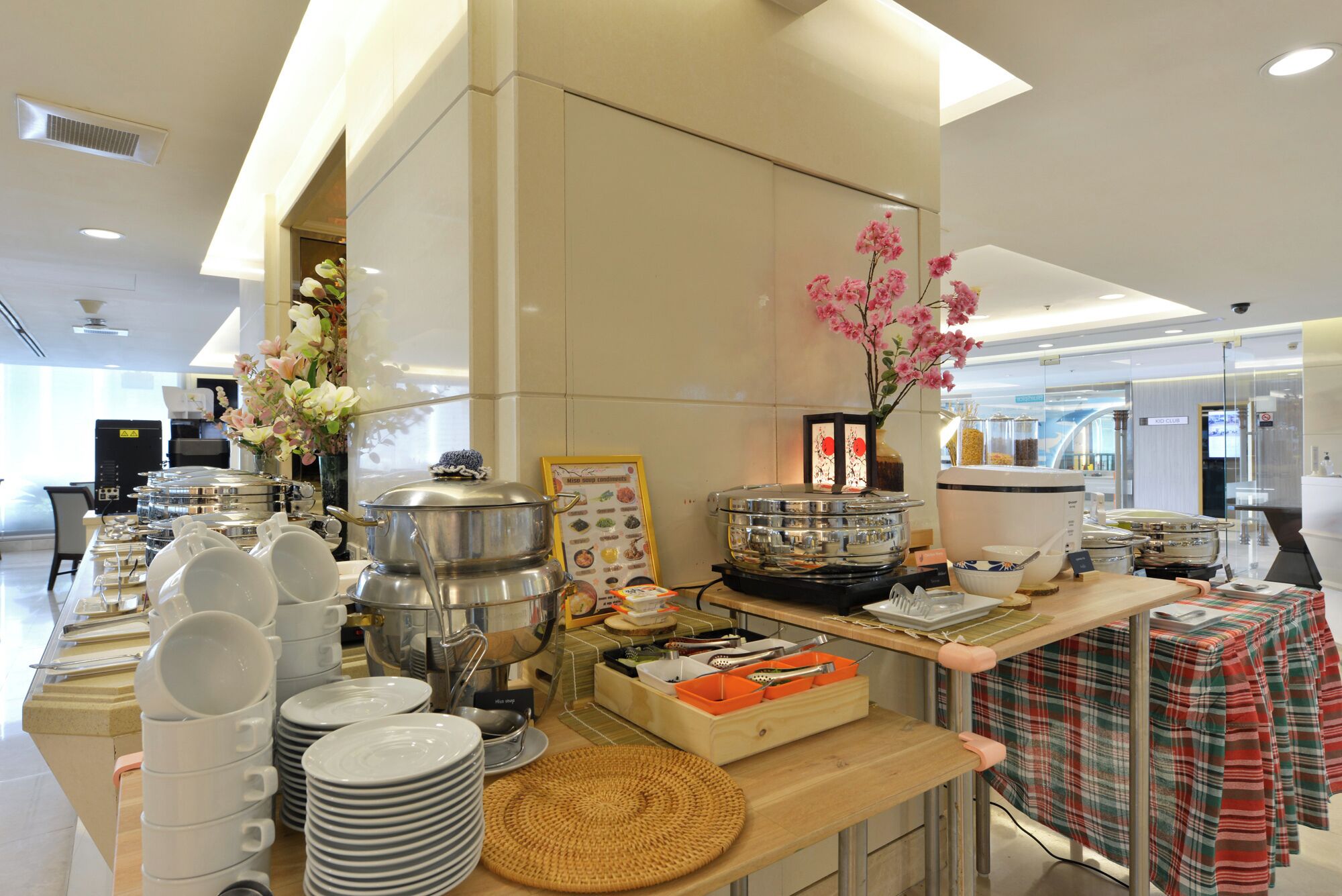 Een buffetopstelling met diverse gerechten, bestek en een decoratieve vaas met bloemen.