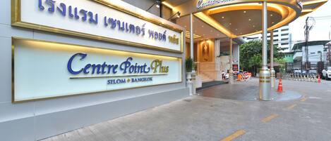 L'ingresso del Centre Point Plus a Silom, Bangkok, con un cartello ben visibile e un'area d'ingresso coperta.