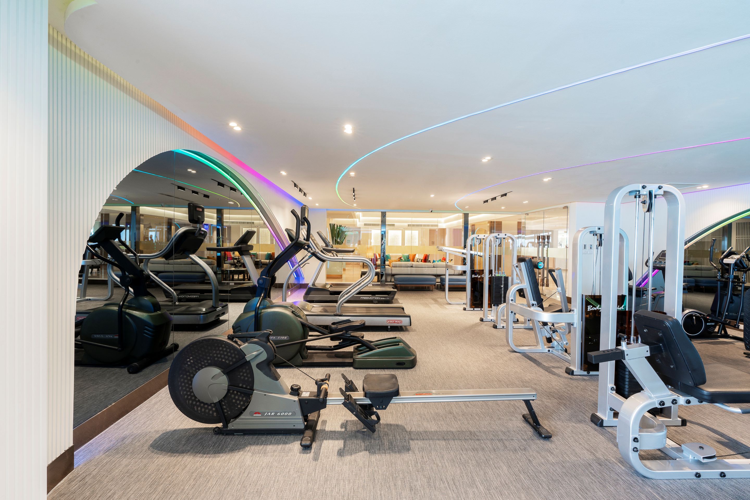 Un gimnasio moderno con diversos equipos de ejercicio, incluyendo cintas de correr, bicicletas estáticas y máquinas de pesas.