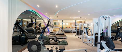 Un gimnasio moderno con diversos equipos de ejercicio, incluyendo cintas de correr, bicicletas estáticas y máquinas de pesas.