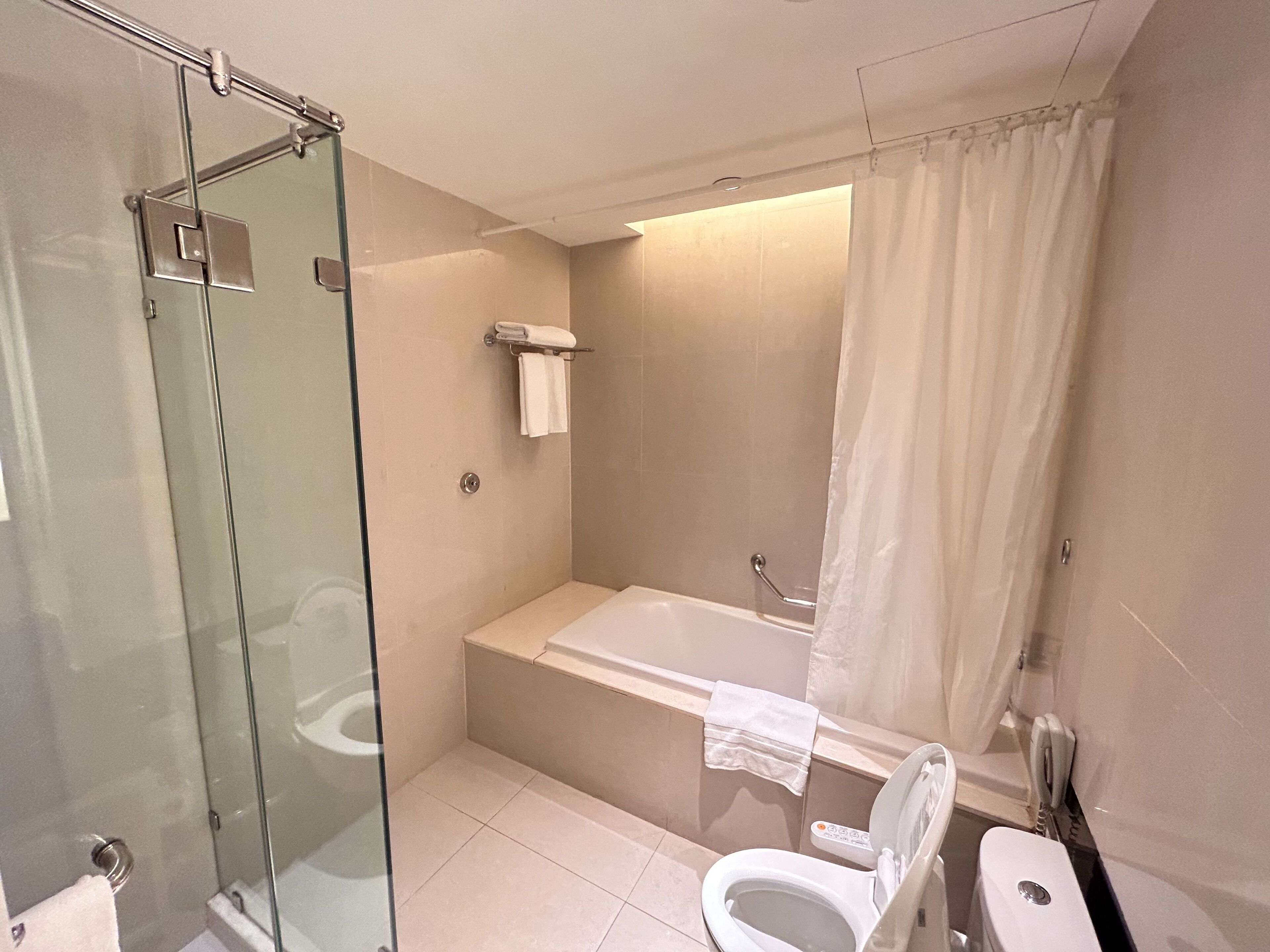 A modern bathroom with a glass shower enclosure, a bathtub, and a toilet.