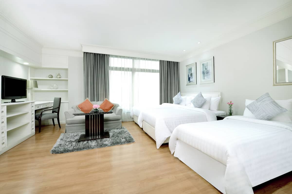A hotel room with two beds, a desk, a chair, a TV, and a window with curtains.