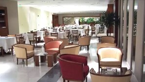 A spacious hotel lobby with multiple seating areas, including armchairs and tables, arranged in a modern layout.