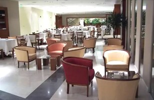 Un amplio vestíbulo de hotel con varias zonas de estar, incluyendo sillones y mesas, dispuestas en una distribución moderna.