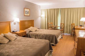 A hotel room with two beds, a desk, a chair, a lamp, and a window with curtains. - Howard Johnson by Wyndham Rio Cuarto Casino (Rio Cuarto)