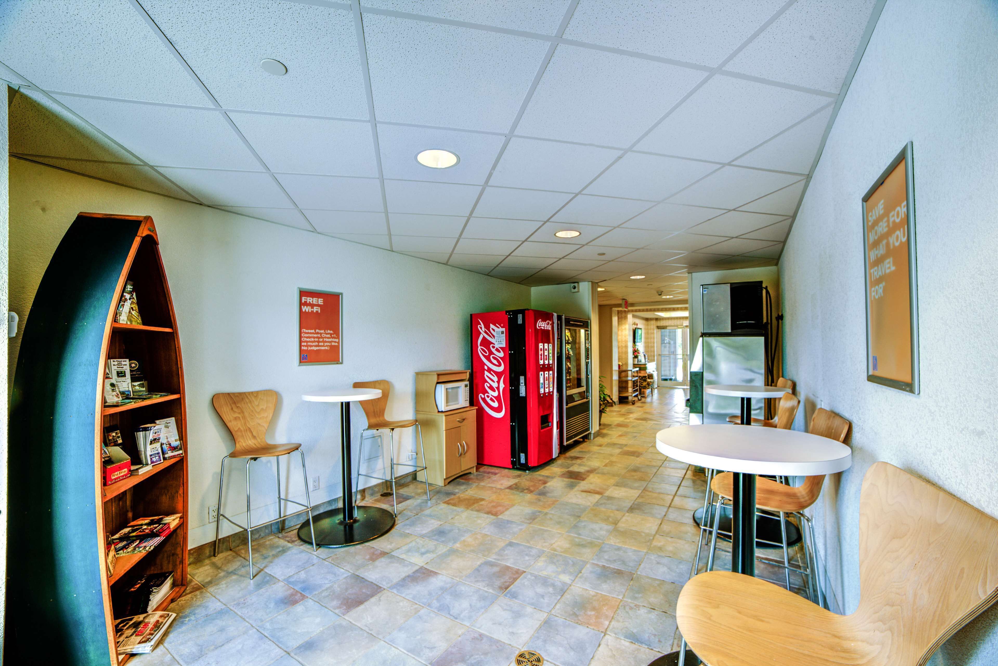 A hallway with seating areas, vending machines, and informational signs.