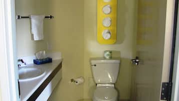 Ein Badezimmer mit Toilette, Waschbecken und einer gelben Seifenschale an der Wand.
