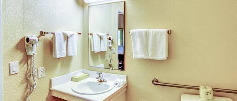Un baño con lavabo, espejo, toallero y retrete.