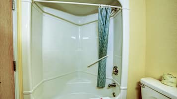 Ein Badezimmer im Eckbereich mit Badewanne, Duschvorhang und Toilette.