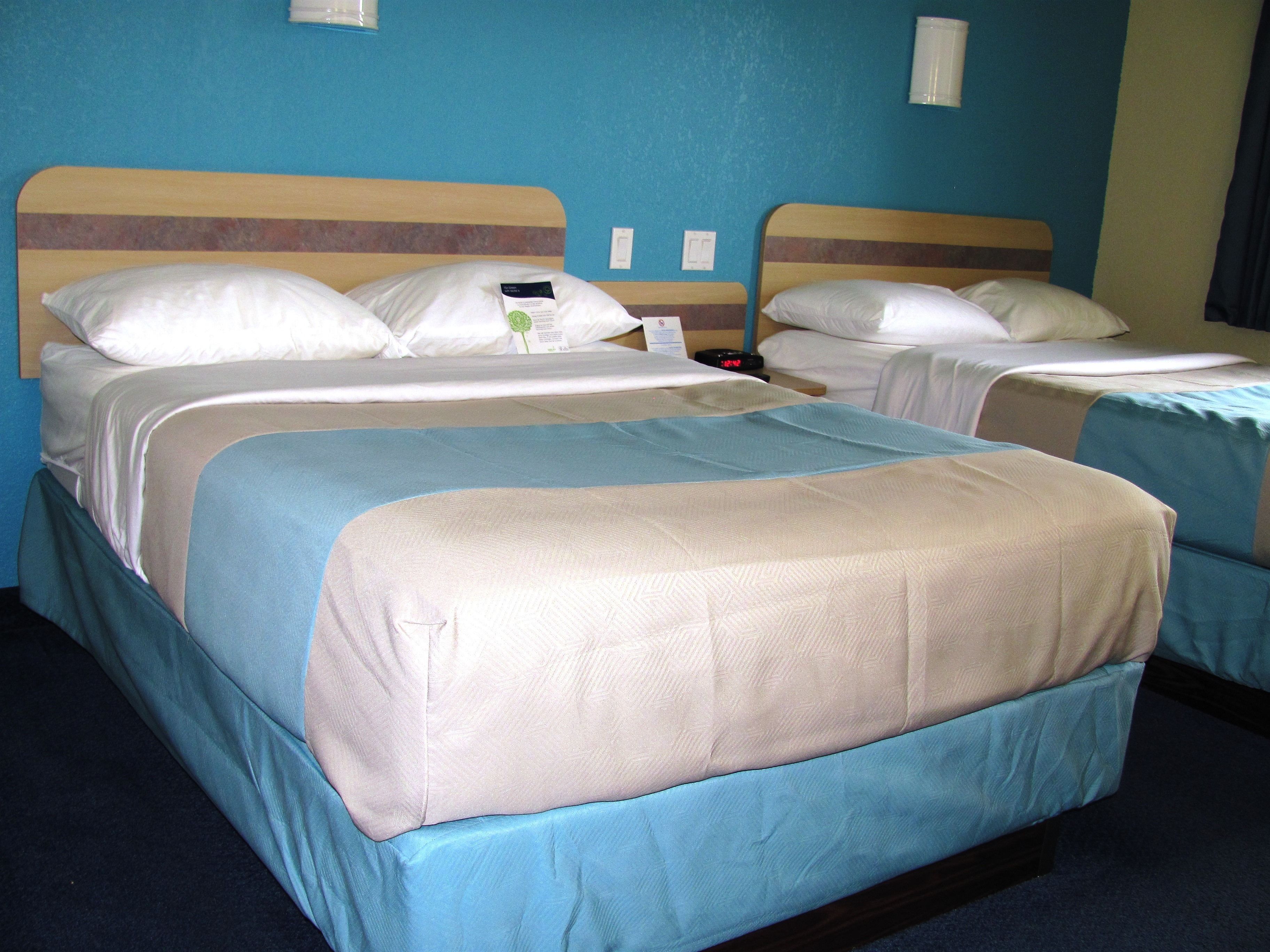 Une chambre d’hôtel avec deux lits, chacun recouvert d’une courtepointe bleue et beige, et dotée d’une tête de lit en bois.