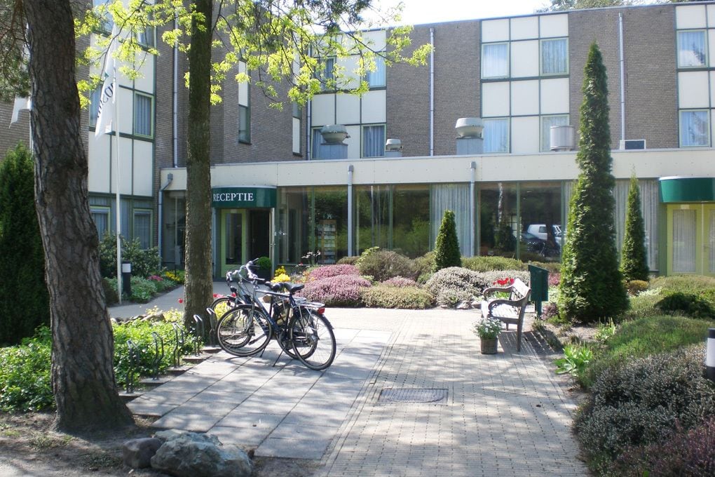 Un bâtiment doté d’un espace d’accueil, de vélos garés à l’extérieur et d’un jardin bien entretenu, agrémenté de bancs et d’arbres.