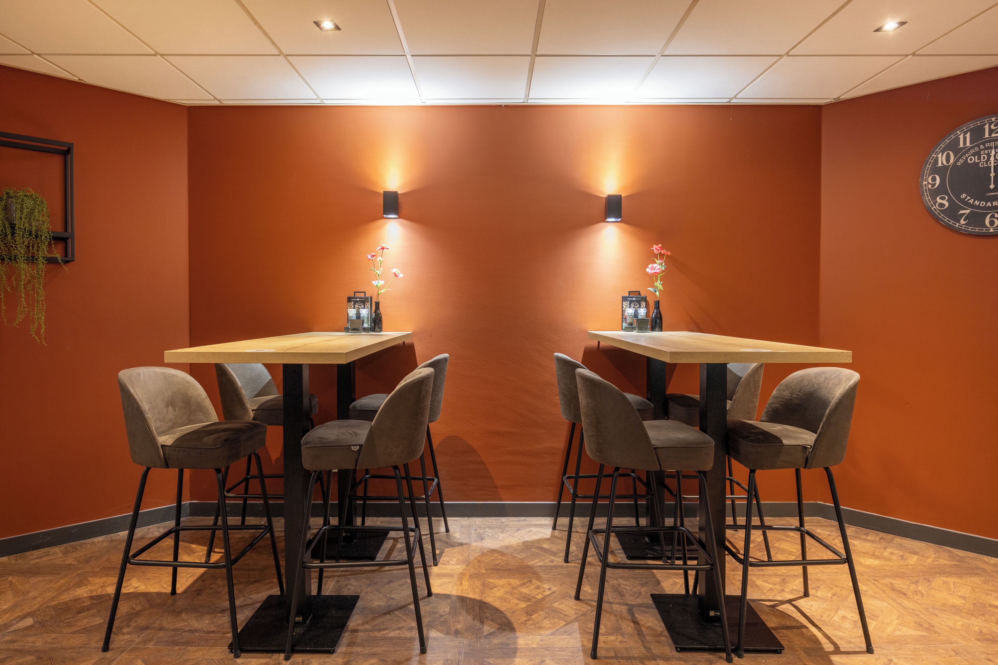 A conference room with two tables and four chairs, a clock on the wall, and wall-mounted lights.