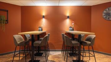 A conference room with two tables and four chairs, a clock on the wall, and wall-mounted lights.