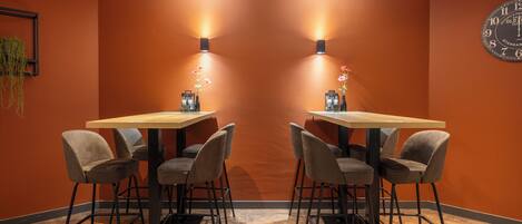 A conference room with two tables and four chairs, a clock on the wall, and wall-mounted lights.