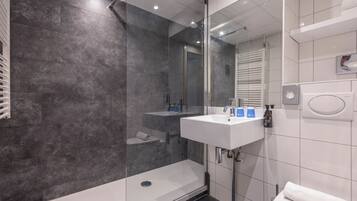 Une salle de bain moderne avec une douche à parois de verre, un lavabo blanc et des toilettes.