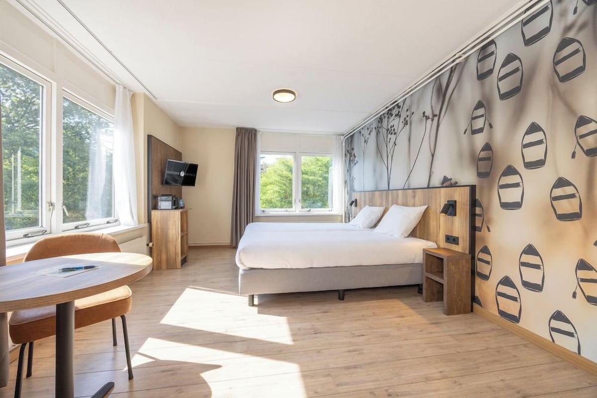 A bedroom with a bed, a desk, a chair, and a TV.