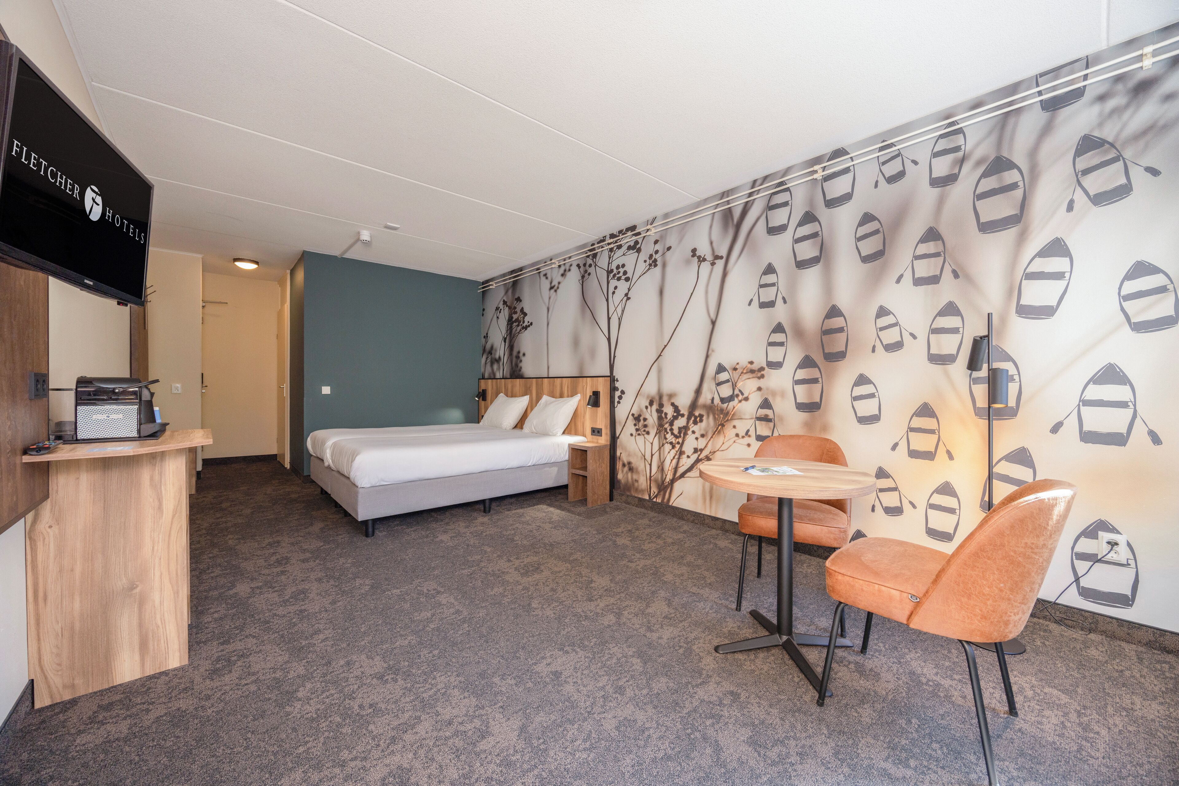 Une chambre d’hôtel avec un lit, un bureau, une chaise et un téléviseur.