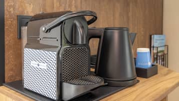 Una cafetera con asa, un hervidor y una taza de café sobre una encimera de madera.