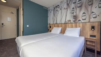 Una cama doble con ropa blanca, un cabecero de madera y una pared con diseño náutico.