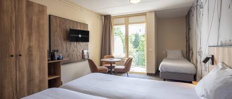 A hotel room with a bed, a desk, a chair, a television, and a balcony with a view.