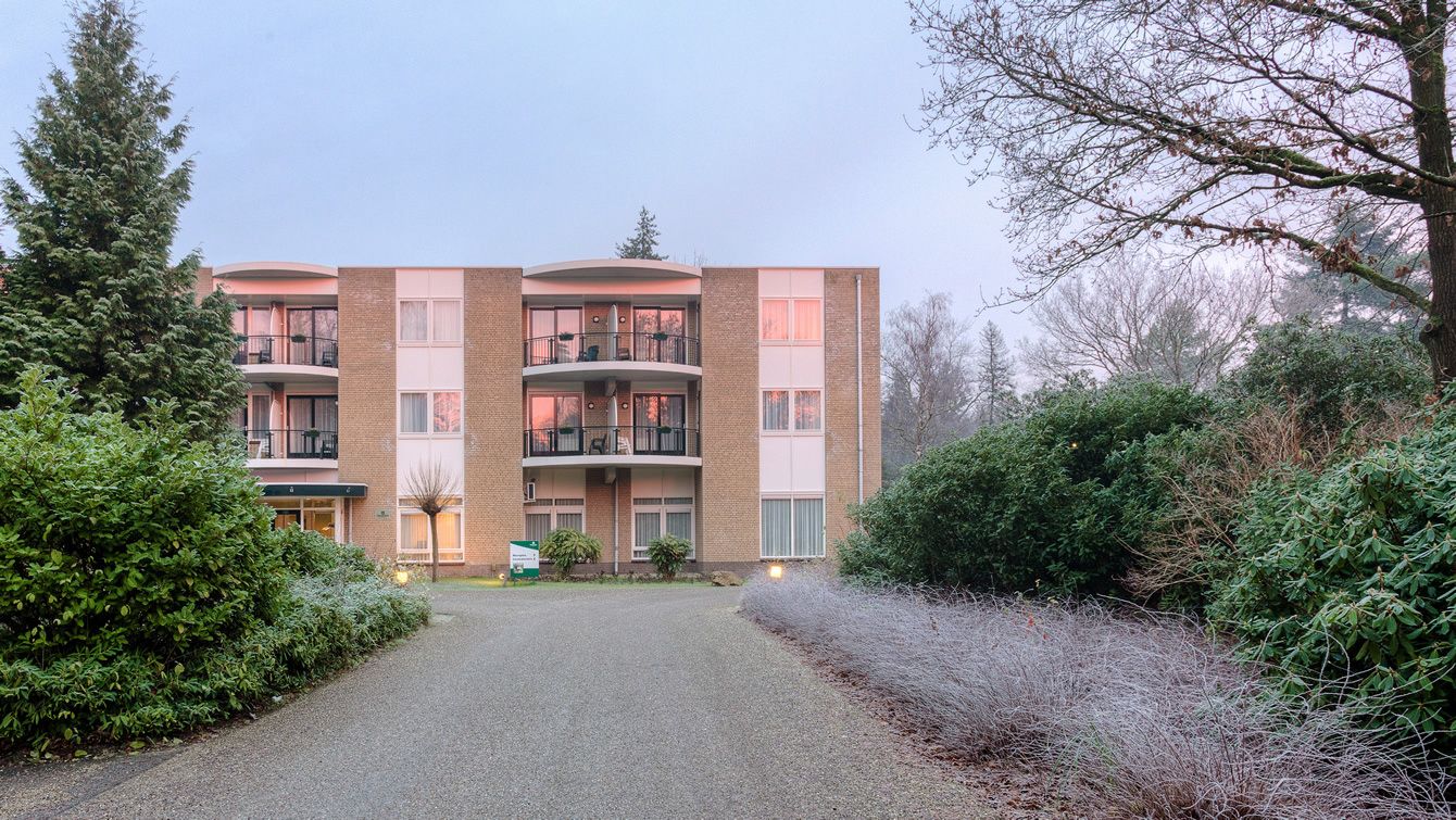 Un edificio de varios pisos con un patio central, rodeado de abundante vegetación y árboles.
