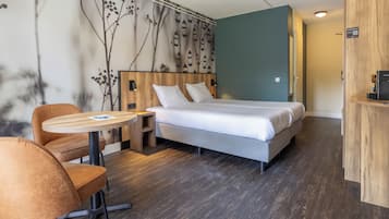 A modern hotel room with a bed, a round wooden table, and a chair.