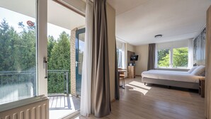 Quarto de hotel moderno com varanda, uma cama, escrivaninha e televisão.