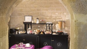 Een ontbijtbuffet in een kamer met stenen muren, een tafel en stoelen.