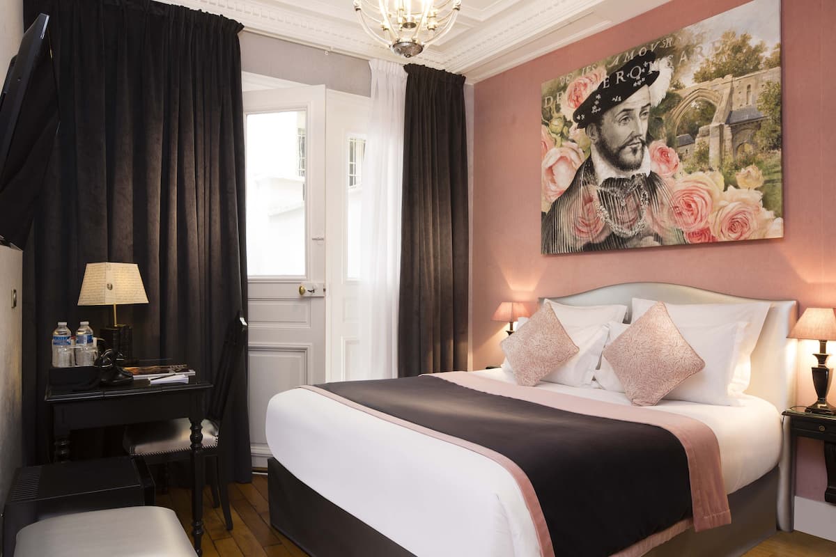 Habitación de hotel con una cama grande, un escritorio, una silla y un cuadro en la pared.