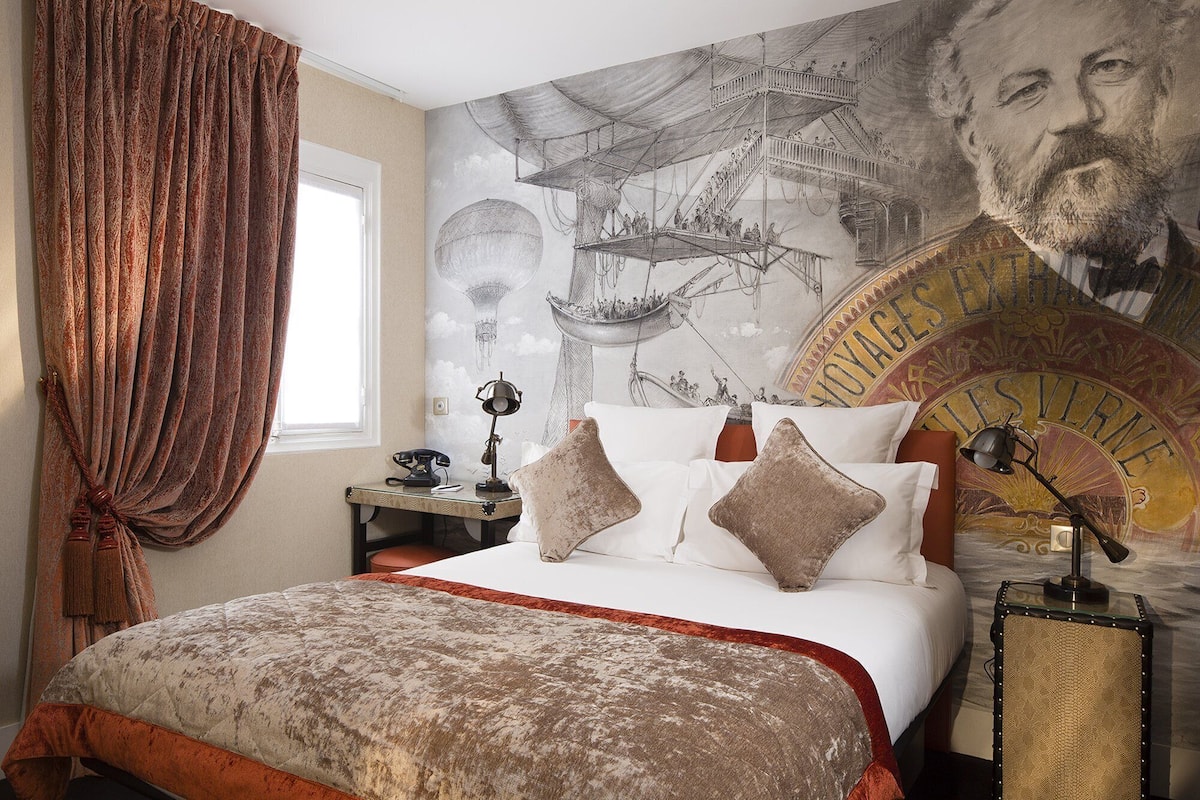 Un dormitorio con una cama grande, un teléfono antiguo, una lámpara y un mural en la pared.